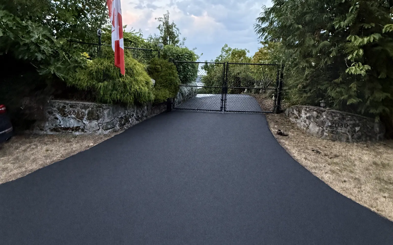 Gated estate entrance freshly sealcoated, dark protective finish to the gate line