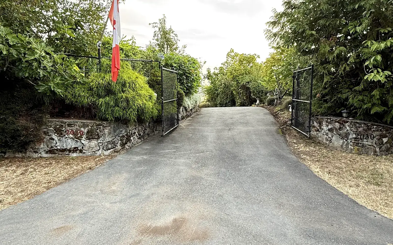 Same gated entrance before sealing, faded grey asphalt