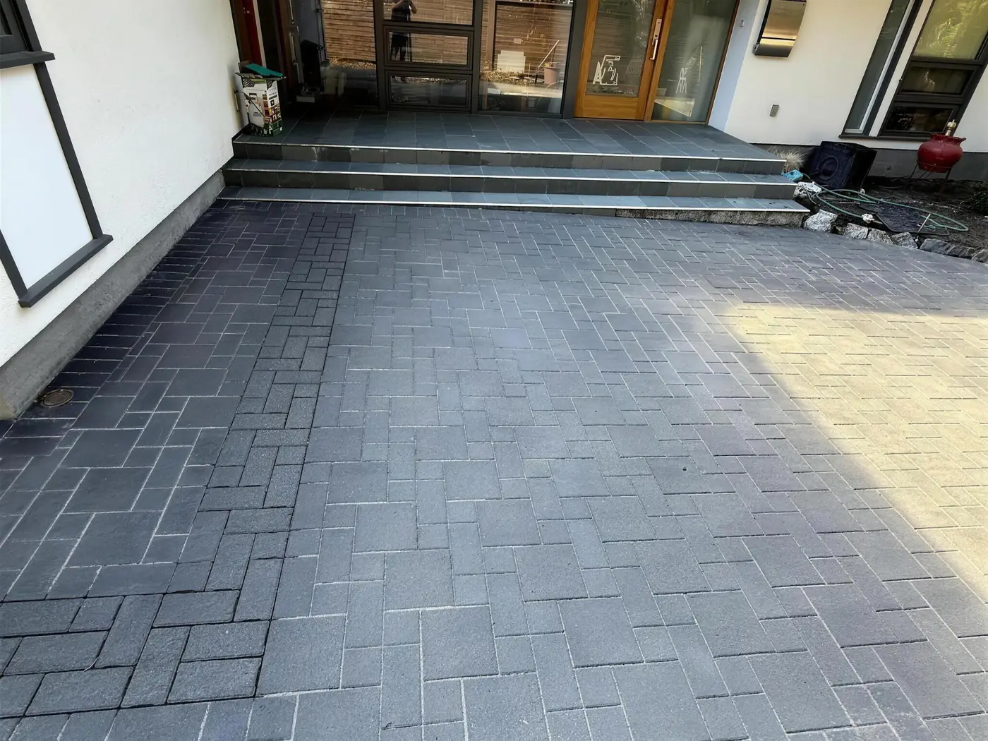 Charcoal paver driveway mid-seal showing the wet-look seal line
